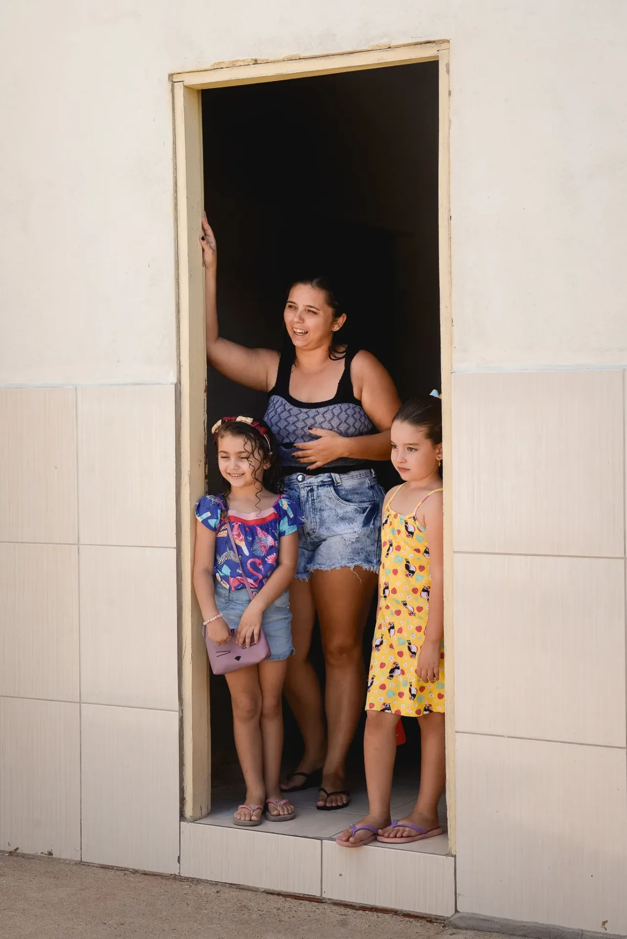 Mulher e crianças na porta de casa vendo a movimentação dos Amarelinhos do Instituto Livres