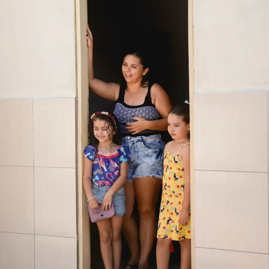 Mulher e crianças na porta de casa vendo a movimentação dos Amarelinhos do Instituto Livres
